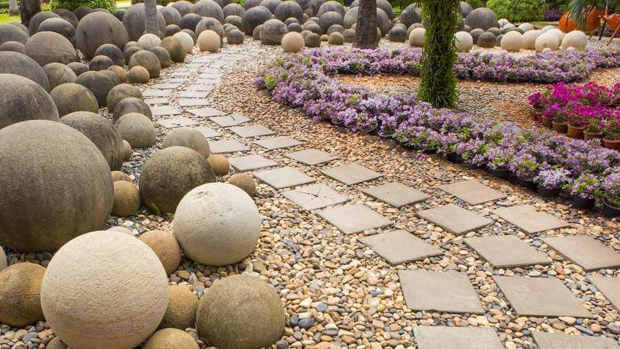 Curved granite flagstone pathway with cobblestone borders in a garden corner