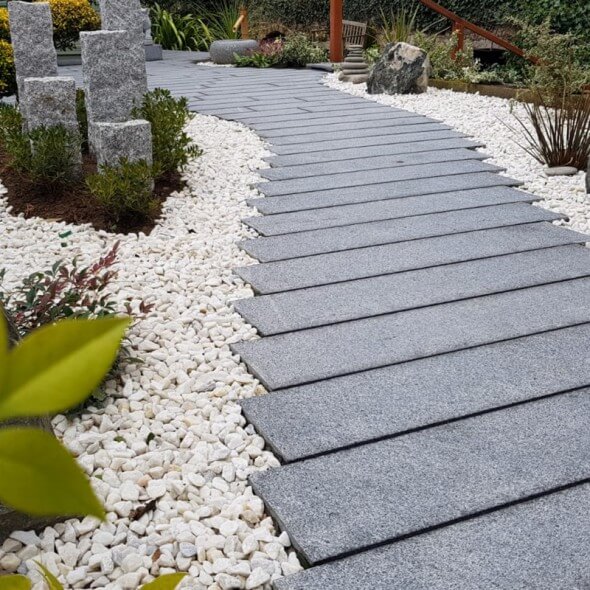 Rectangular granite paver pathway with white cobblestone edging and decorative granite pillars